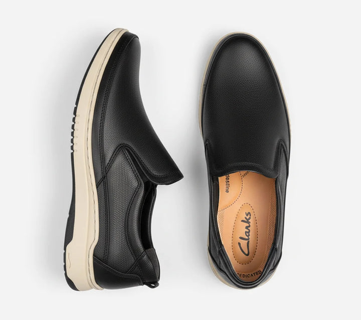 Black slip-on shoes with white soles on a light gray background