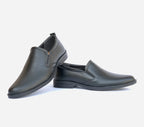 Pair of black slip-on shoes on a light gray background