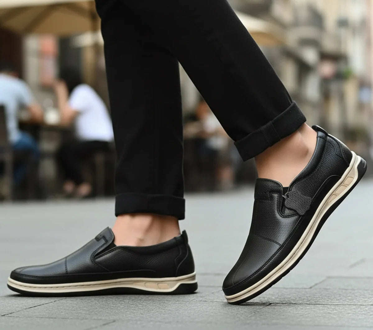 Black loafers worn with black pants on a blurred street background