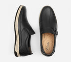 Black slip-on shoes with 'Clarks' branding on a white background