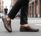 Person wearing brown loafers on a city street