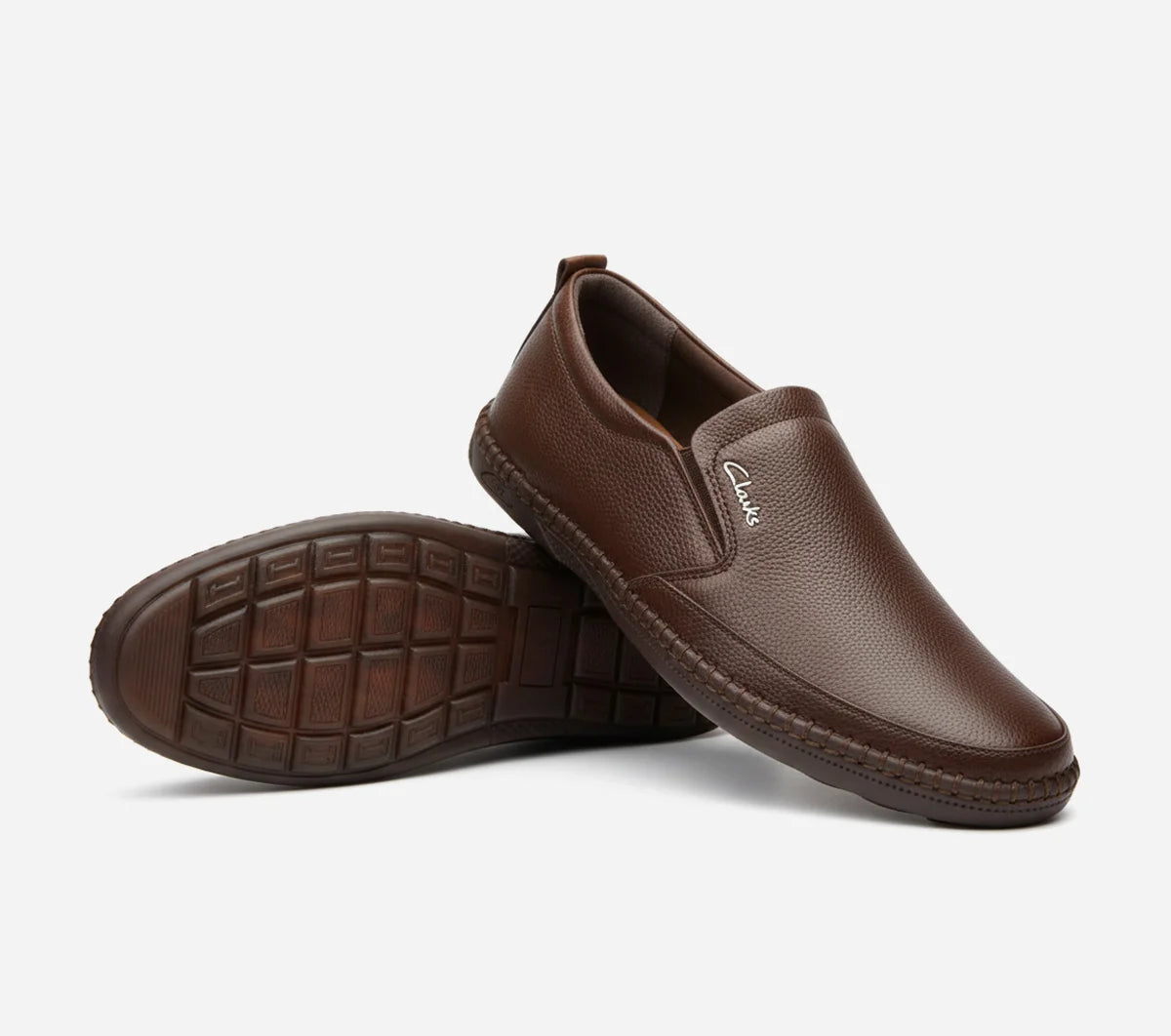 Brown slip-on shoes with a visible brand logo on a light gray background