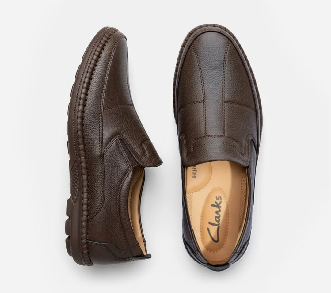 Pair of brown loafers with Clarks logo on a light gray background