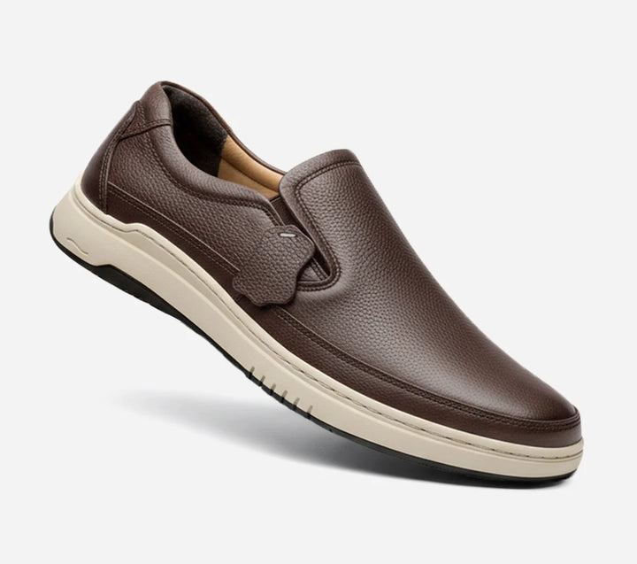 Brown slip-on shoe with a white sole on a light gray background