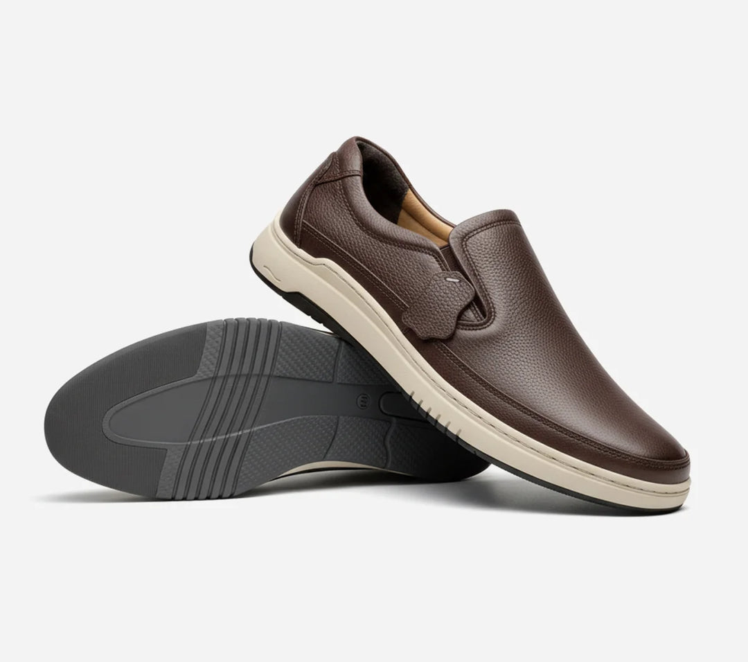 Brown slip-on shoes with a white sole on a light gray background