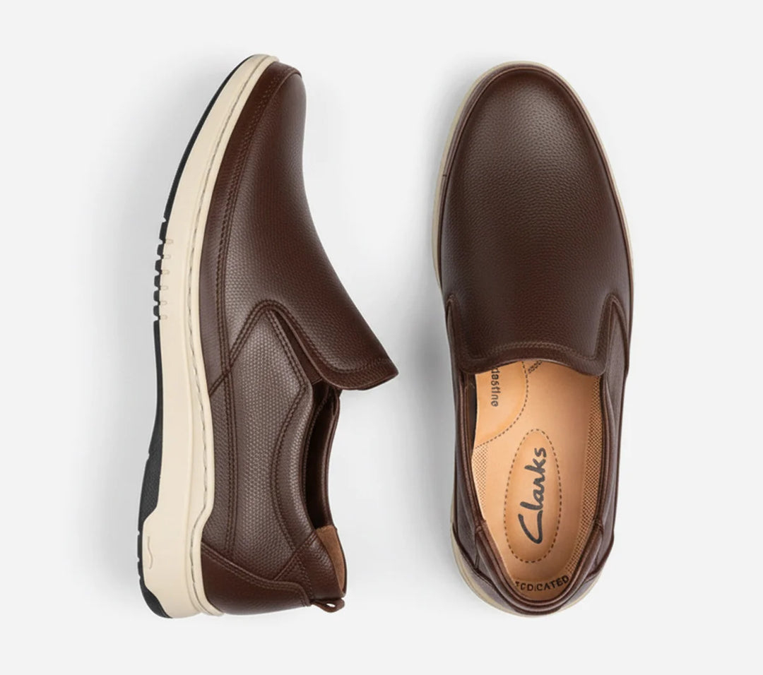 Brown slip-on shoes with white soles on a light gray background