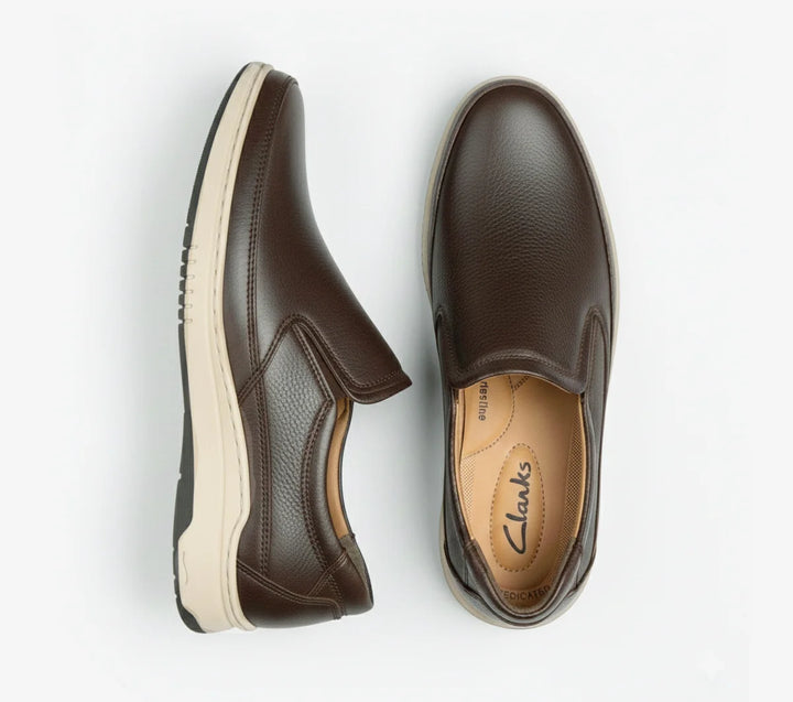 Pair of brown slip-on shoes with white soles on a light gray background