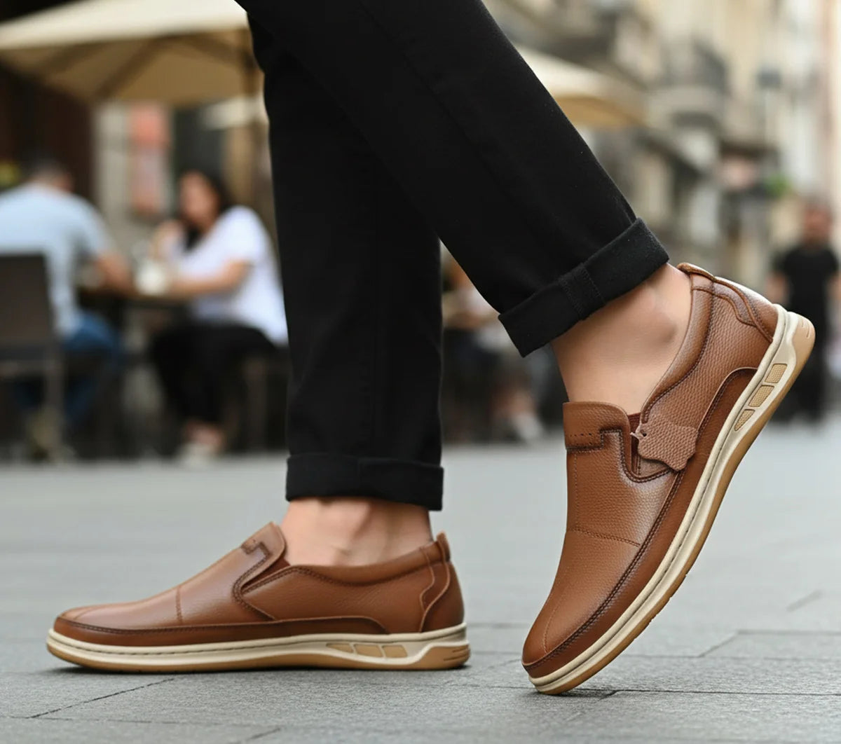 Brown loafers worn on a city street with blurred people in the background